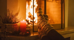 person wearing christmas socks by an open fire